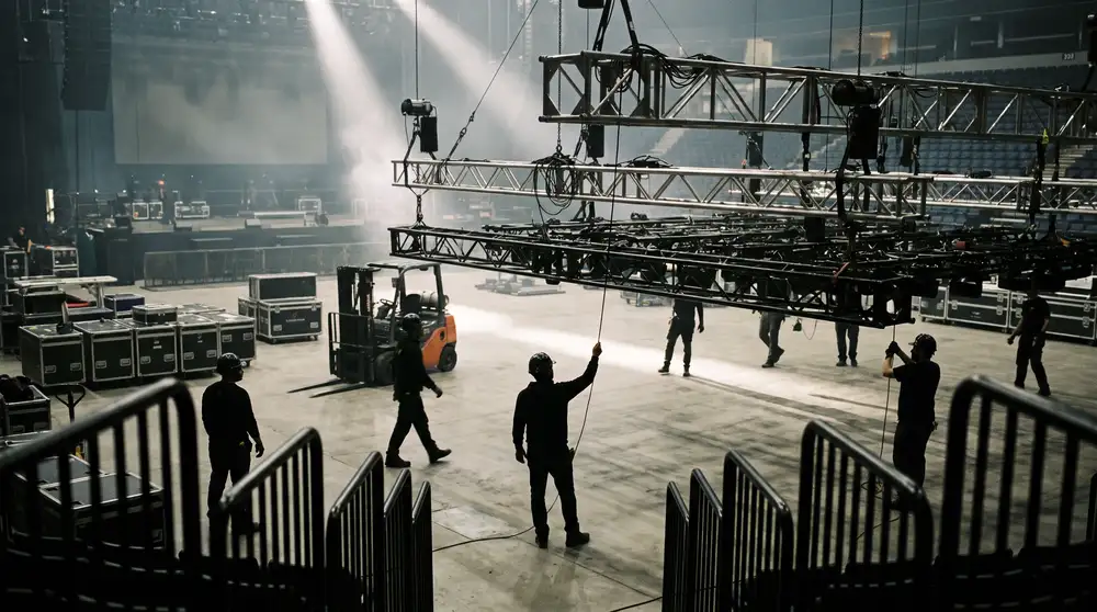 Event crew rigging a lighting truss inside an empty arena