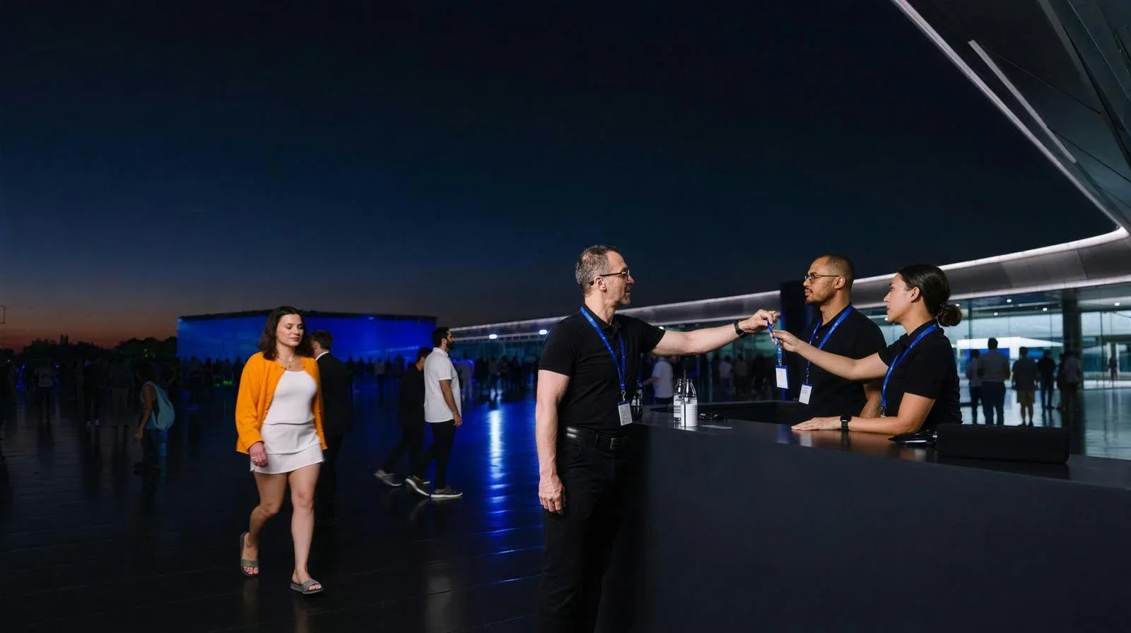 Event staff handing a credential badge to a guest at an evening event